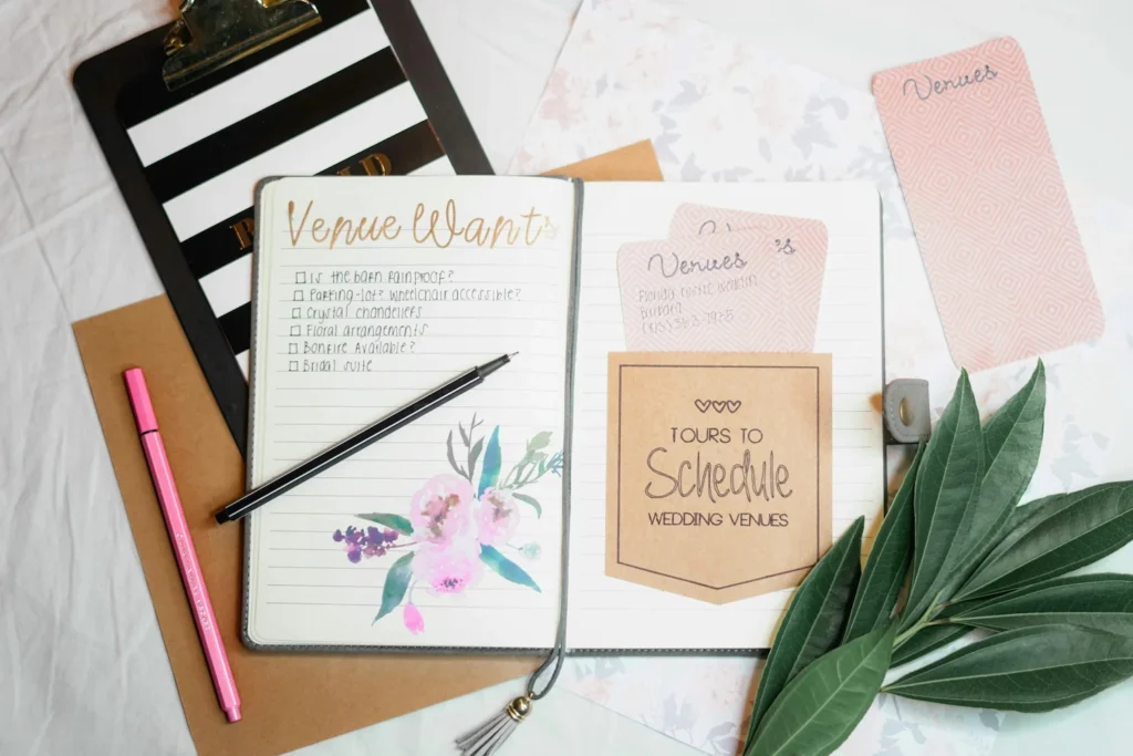 Wedding planning checklist with venue notes, pen, and leaves on a desk — symbolizing organized event preparation