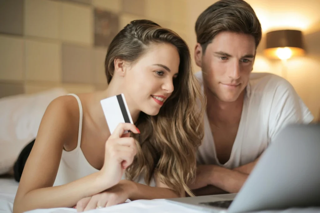 Smiling couple booking event services online with a credit card on a laptop — easy and secure reservation experience